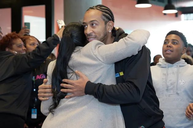 Ludacris embraces a woman wearing a grey coat.